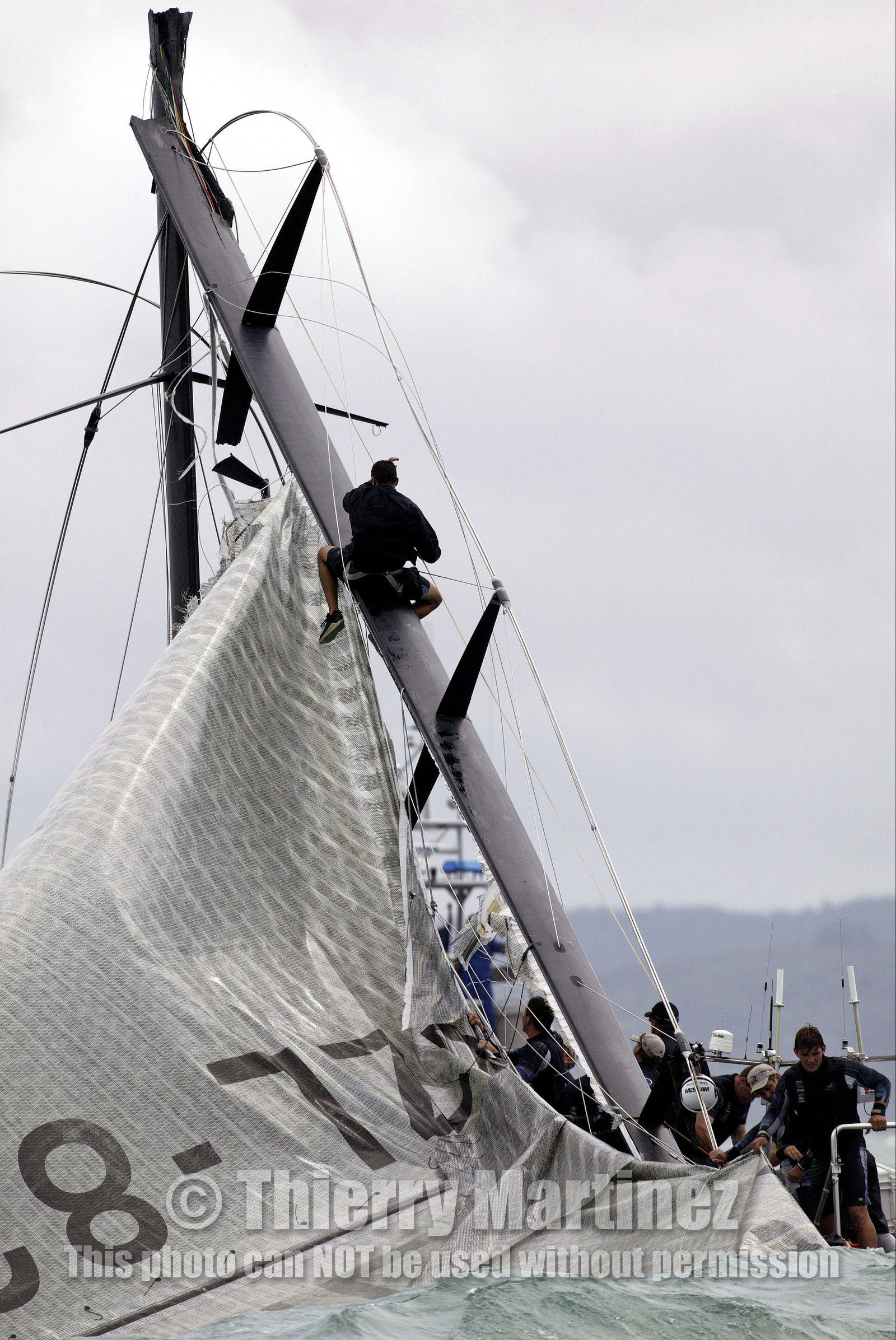03_0258D ©Th.Martinez - Auckland (NZ) . America's Cup  2003. 28th February 2003. Day 4 .Alinghi (SUI 64) vs Team NZ (NZL 82) .Team NZ's boat dismast 57 minutes after the start in only 18 knots of windwith a swell of 1.5 m. Team NZ crew trying to take off the mainsail  on the broken mast. Alinghi is leading Team NZ  4-0 after 4 races.