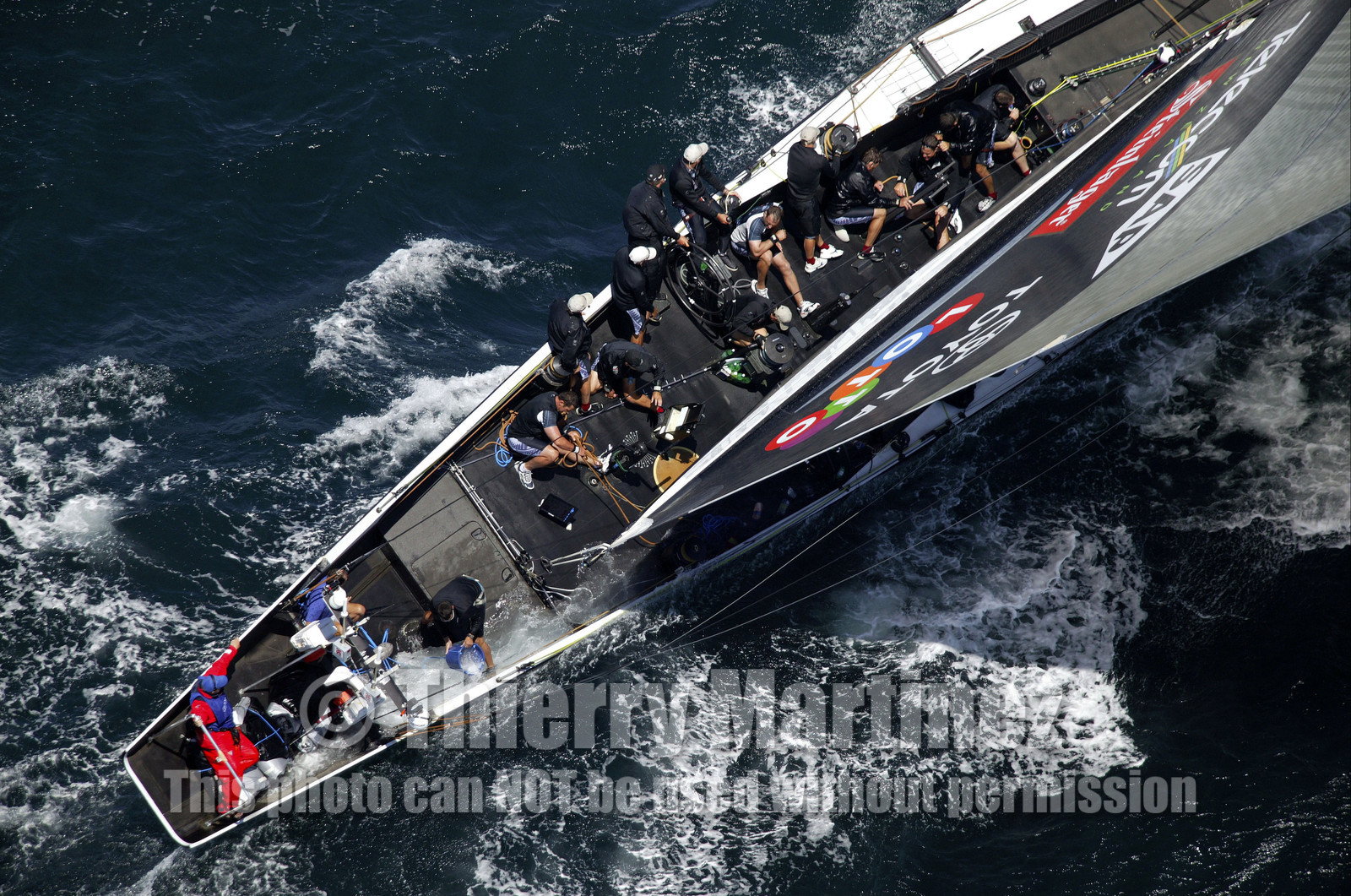 03_0165D ©Th.Martinez - Auckland (NZ) . America's Cup 2003. 15th February 2003. Day 1..Alinghi (SUI 64) vs Team NZ (NZL 82) .NZL 82 in first minutes of Race 1 before retiring on damage..Matt Miichell (Team NZ midbowman) bailing water out of NZL 82. .