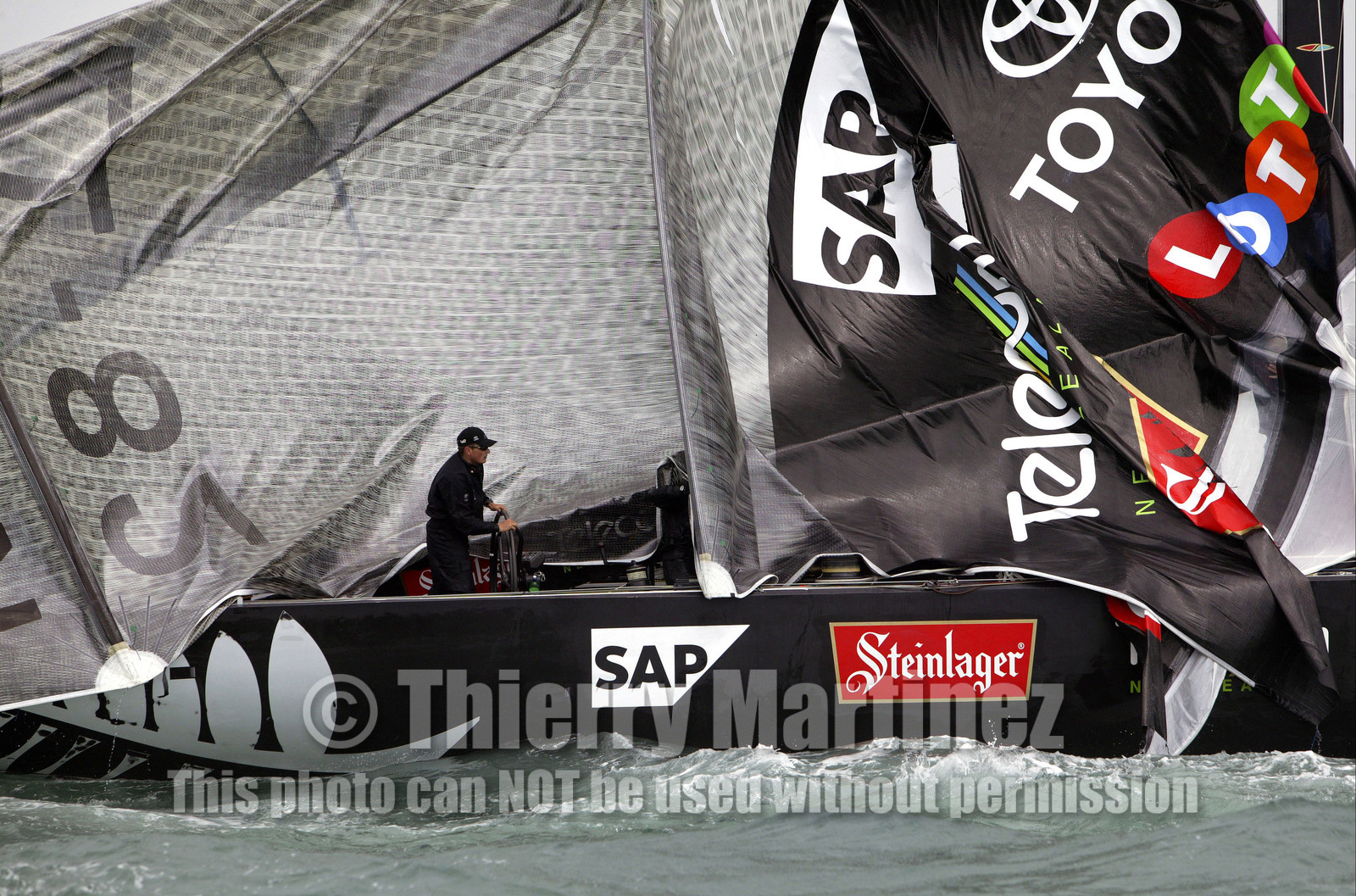 03_0254D ©Th.Martinez - Auckland (NZ) . America's Cup 2003. 28th February 2003. Day 4 .Alinghi (SUI 64) vs Team NZ (NZL 82) .Team NZ's boat dismast 57 minutes after the start in only 18 knots of windwith a swell of 1.5 m. Dean Barker still at the helm, with main sail and mast on deck. Alinghi is leading Team NZ  4-0 after 4 races.