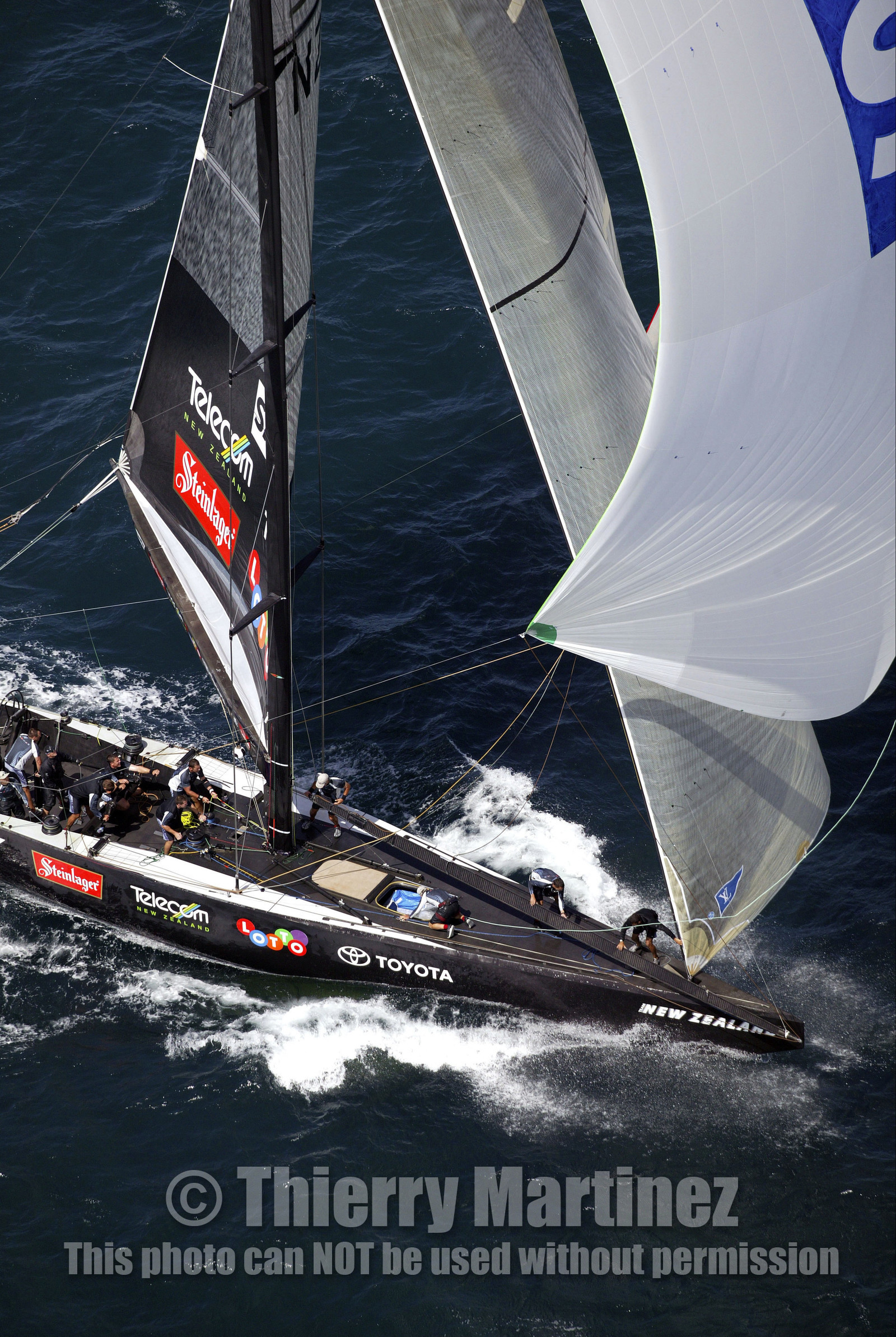 03_0196D ©Th.Martinez - Auckland (NZ) . America's Cup 2003. 18th February 2003. Day 3..Alinghi (SUI 64) vs Team NZ (NZL 82) .Team NZ 's crew droping head sail after setting up spinnaker at upwind mark.....