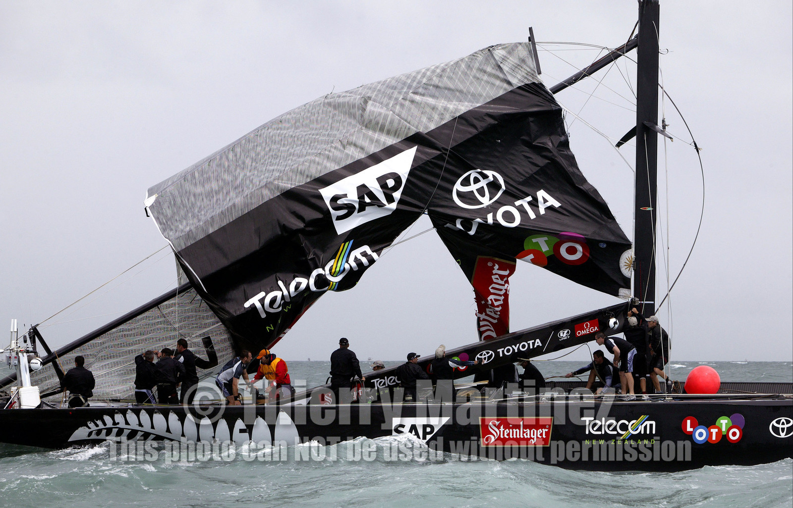 03_0255D ©Th.Martinez - Auckland (NZ) . America's Cup 2003. 28th February 2003. Day 4 .Alinghi (SUI 64) vs Team NZ (NZL 82) .Team NZ's boat dismast 57 minutes after the start in only 18 knots of windwith a swell of 1.5 m.  Team NZ crew trying to take off the main sail from the broken mast.. Alinghi is leading Team NZ  4-0 after 4 races.